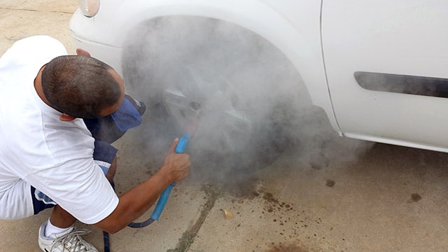 Mobile car wash operator cleaning brake dust from car rims with an Optima Steamer.