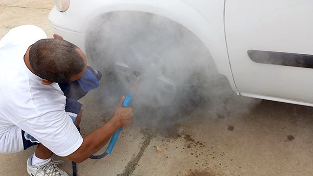 Mobile car wash operator cleaning brake dust from car rims with an Optima Steamer.