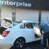 Rental car employee sanitizing a white car interior with the Optima Steamer