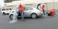 Two mobile car wash operators cleaning a car interior and exterior with the Optima Steamer