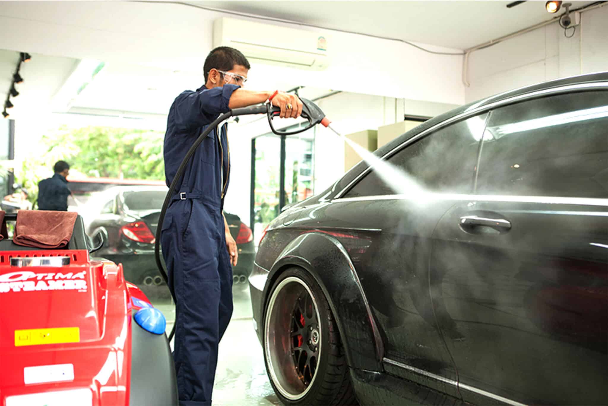 Car wash operator cleaning a car's exterior with an Optima Steamer