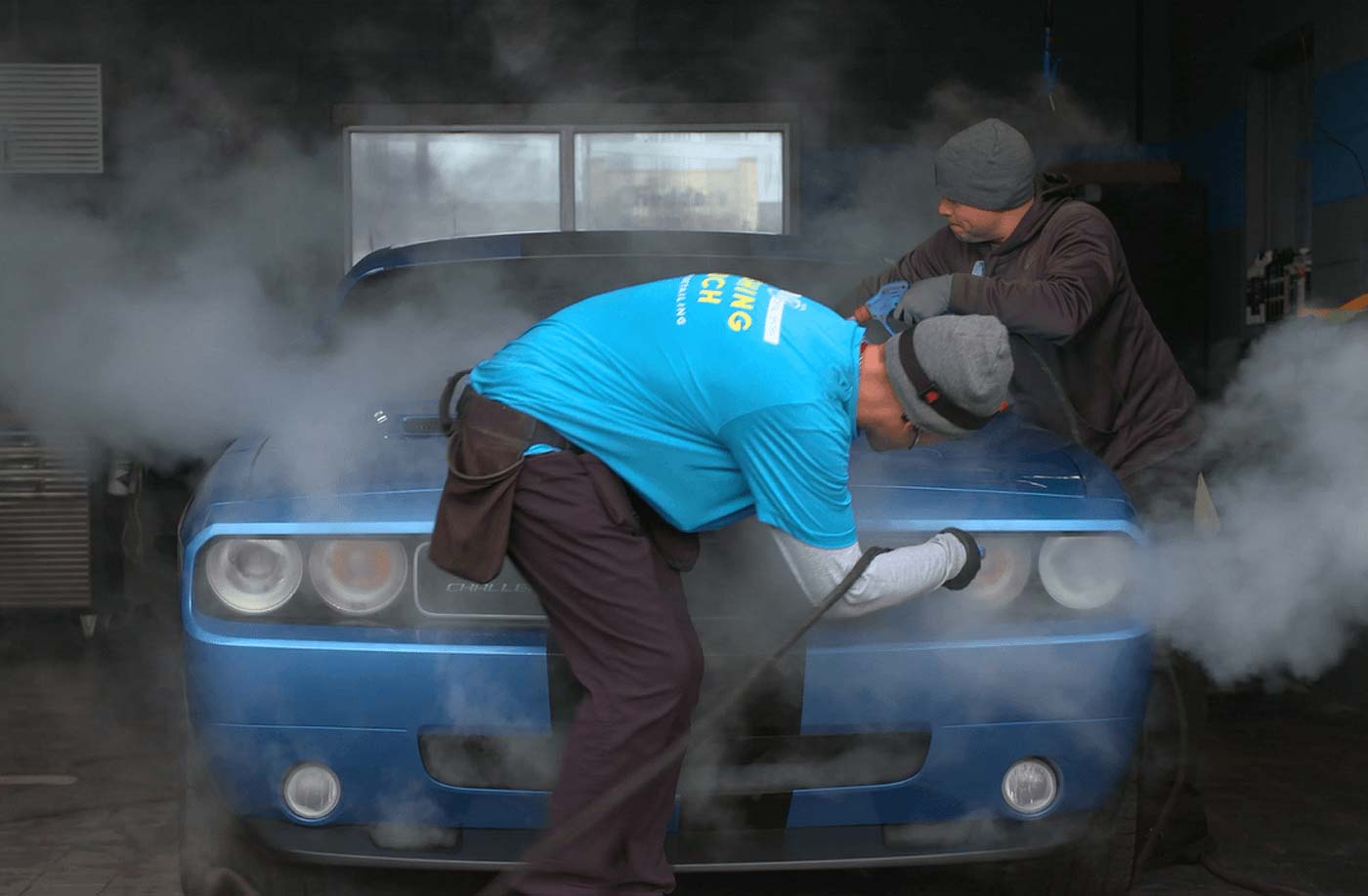 steam cleaning the front of a blue car
